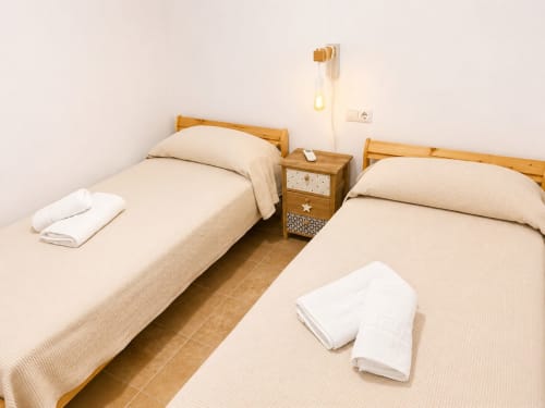 Twin beds with wooden frames and white towels in Alzara cottage at Living Sur, Sanlúcar de Barrameda