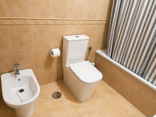 Modern bathroom in Alzara cottage at Living Sur Sanlúcar de Barrameda with toilet, bidet, and beige tile walls
