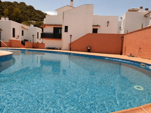 Swimming pool at Living Sur cottage apartments in Sanlúcar de Barrameda with white buildings and terracotta accents