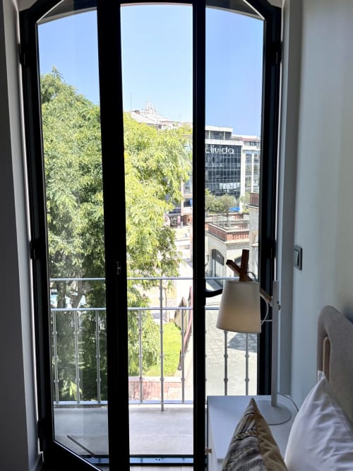 Portes vitrées ouvertes sur la vue de la ville d'Aveiro avec arbres et bâtiments depuis la chambre Premium Silver du RIA CENTRUM