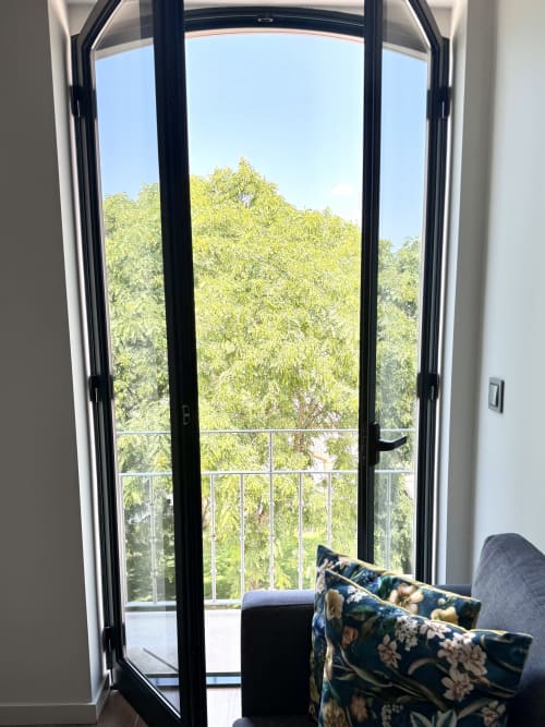 Portes-fenêtres ouvertes de la chambre Premium Green du RIA CENTRUM Aveiro donnant sur la verdure luxuriante et la vue sur la ville