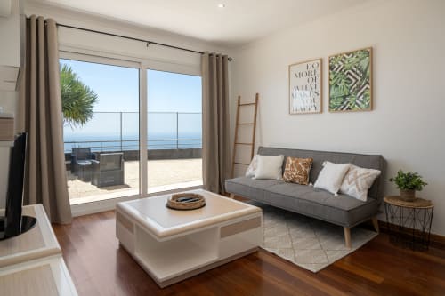 Apartamento moderno com vista para o mar em Caniço, sofá cinzento, acesso a varanda costeira e mobiliário contemporâneo