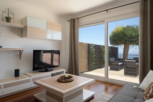 Sala de estar moderna com vista para o mar no Blue Horizon, Caniço, com TV e acesso à varanda com terraço de palmeiras