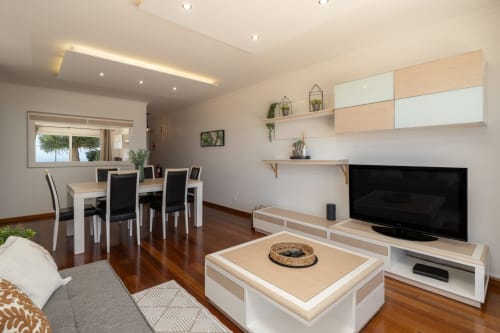 Sala de estar moderna em plano aberto com vista para o mar no apartamento Blue Horizon da Rent-A-Key, Caniço, com área de refeições e TV