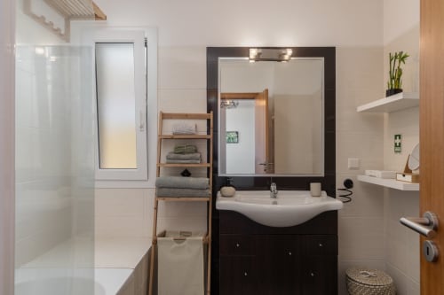 Banheiro moderno do apartamento Blue Horizon na Rent-A-Key, Caniço com bancada escura, pia branca, espelho e box de duche