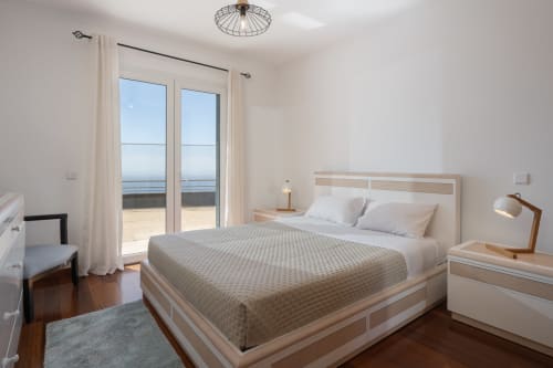 Quarto moderno e luminoso com cama de casal, varanda com vista para o mar e acesso à praia no apartamento em Caniço