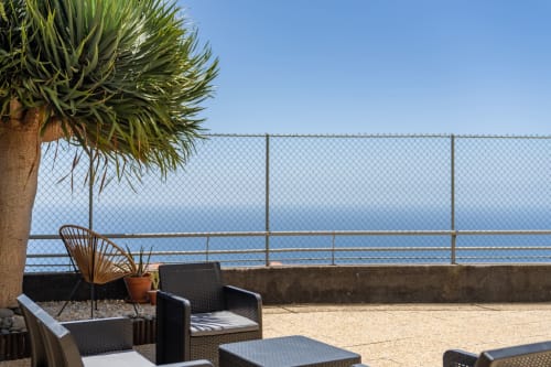 Terraço frente ao mar do apartamento Blue Horizon em Caniço com área de estar, palmeira e vista para o mar através de cerca de segurança