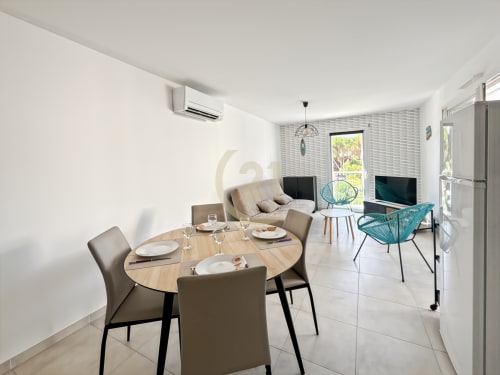 Appartement moderne à Calvi avec table ronde, chaise turquoise, canapé beige et accès à la terrasse