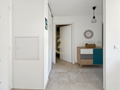 Couloir moderne à Calvi avec carrelage, portes blanches, luminaires suspendus et mobilier en bois aux accents bleu-vert