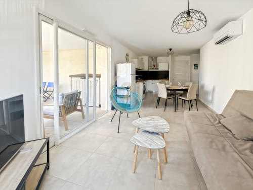 Appartement moderne à Calvi avec séjour ouvert, cuisine, salle à manger, fauteuil bleu et accès terrasse