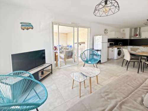 Appartement T2 moderne à Calvi avec salon turquoise, TV écran plat, cuisine et accès à la terrasse