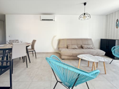 Salon moderne à Calvi avec fauteuils turquoise, canapé beige, salle à manger et décoration contemporaine