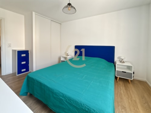 Chambre moderne avec literie turquoise, tête de lit bleue et mobilier contemporain dans l'appartement de Calvi