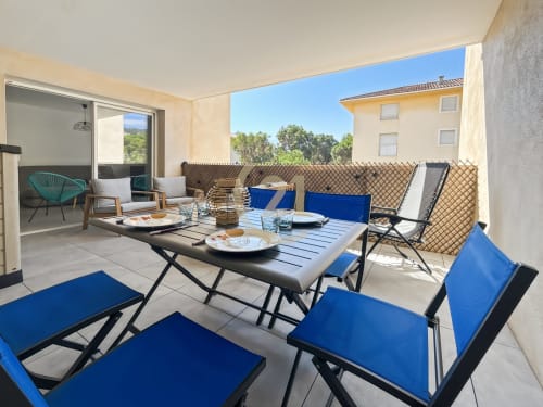 Terrasse spacieuse avec chaises bleues, table de salle à manger et vue sur mer - élégant appartement à Calvi avec parking privé