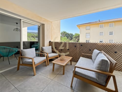 Terrasse moderne avec salon vue sur L'Île-Rousse, Corse. Appartement meublé avec vue sur la ville et coin repas extérieur