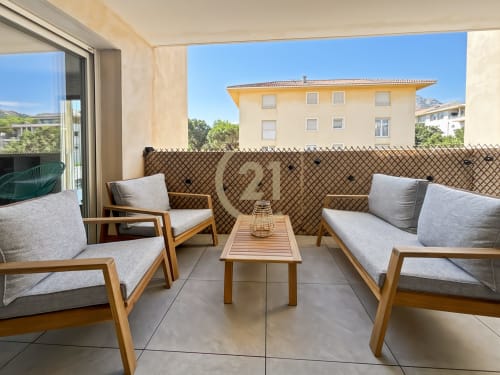 Terrasse moderne à Calvi avec mobilier en bois, coussins gris et vue sur L'Île-Rousse