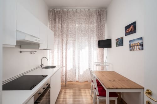 Cucina moderna a Milano con cabinetry bianca, tavolo da pranzo e tende decorate nell'appartamento Duomo Home