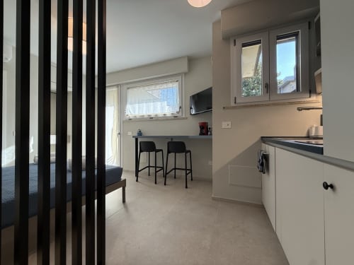 Cucina moderna con mobili bianchi, sgabelli neri e vista mare dell'appartamento La Casetta dei Ronchi a Marina di Massa