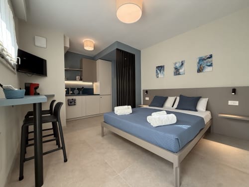 Moderno monolocale a La Casetta dei Ronchi a Marina di Massa con letto, angolo cottura, scrivania e dettagli blu