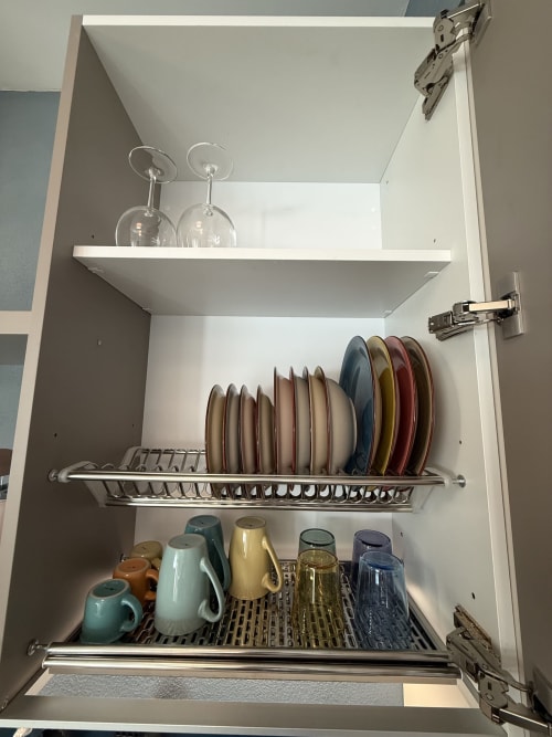 Ante aperte della cucina con scola piatti, bicchieri sospesi, tazze in ceramica e stoviglie all'appartamento La Casetta dei Ronchi, Marina
