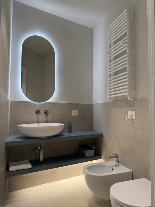 Bagno moderno con specchio ovale illuminato, lavabo a vessel e bidet a La Casetta dei Ronchi, Marina di Massa