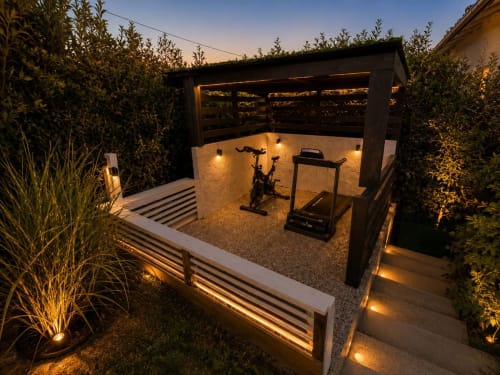 Palestra moderna presso Gan Eden B&B con cyclette, treadmill, illuminazione ambiente e siepi frangivista al tramonto