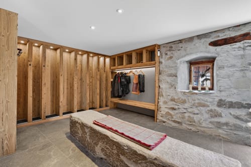Vestiaire du chalet de luxe L'Alp'In avec casiers en bois, murs en pierre et banc chauffant à La Plagne Tarentaise