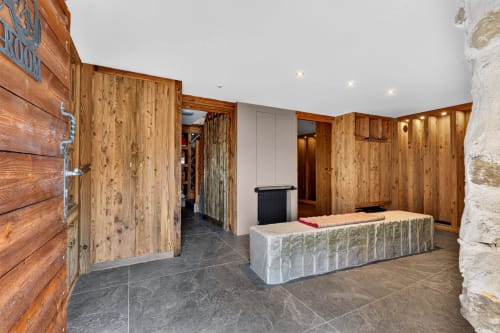 L'Alp'In reception area with wooden doors, stone walls, and slate flooring in La Plagne Tarentaise