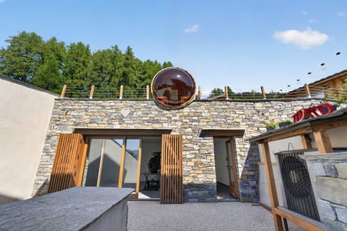 L'Alp'In BnB stone terrace with large copper sphere art installation overlooking trees at La Plagne Tarentaise