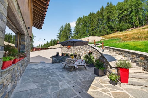 L'Alp'In terrace with stone patio, black umbrella, fireplace, and alpine views in La Plagne Tarentaise