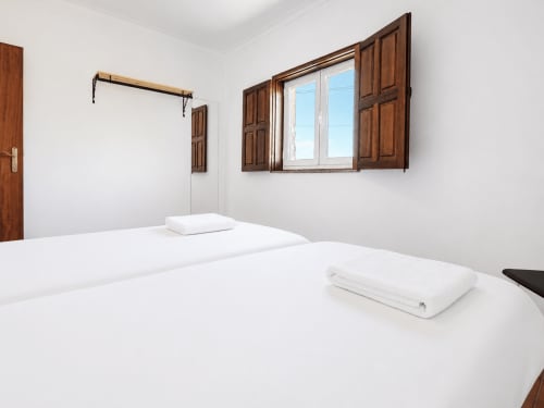 Quarto luminoso na Quinta de Carvalhal em Guimarães com camas gêmeas, roupa branca, venezianas de madeira e vista para o jardim