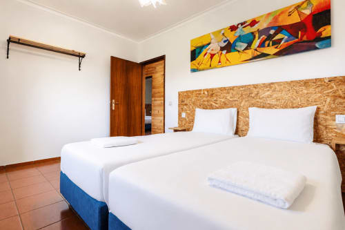 Camas de solteiro com roupa de cama branca e cabeceira de cortiça em quarto moderno do Quinta de Carvalhal, Guimarães