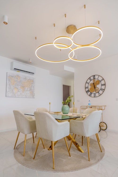 Modern dining room at Suites Avenue Lux with gold pendant lights, cream chairs, and geometric ceiling fixture in Horta.