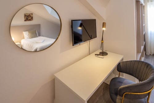 Modern studio room at Suites Avenue Lux Apartments in Horta with desk, TV, circular mirror, and contemporary furnishings