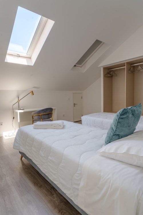 Modern twin bedroom with skylight at Suites Avenue Lux Apartments, Horta, featuring white bedding and wardrobe