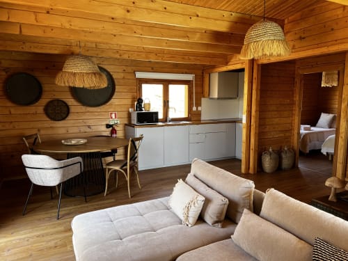 Interior rústico de villa em madeira em Corvatos Casas do Monte com sofá bege, área de refeições, cozinha moderna e luminária decorativa