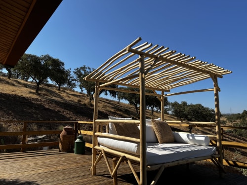 Cama de pérgula em madeira com roupas de cama brancas no terraço da quinta Corvatos Casas do Monte em Almodôvar, Portugal