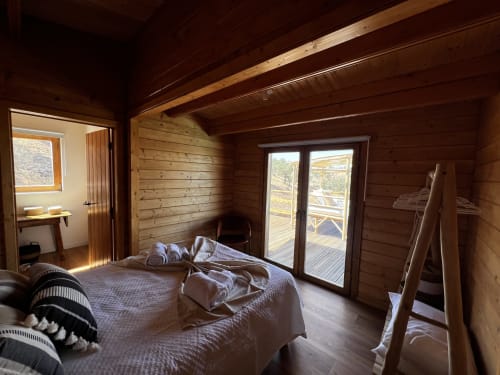 Espaçoso quarto de madeira na villa Casa do Montado em Almodôvar com cama, portas de vidro para terraço e vista da piscina