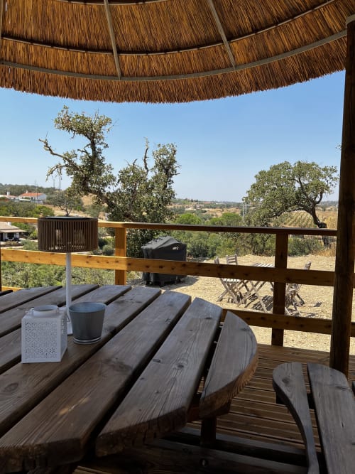 Terraço em madeira com mesa na villa Corvatos Casas do Monte em Almodôvar, com vista para a paisagem rural e oliveiras
