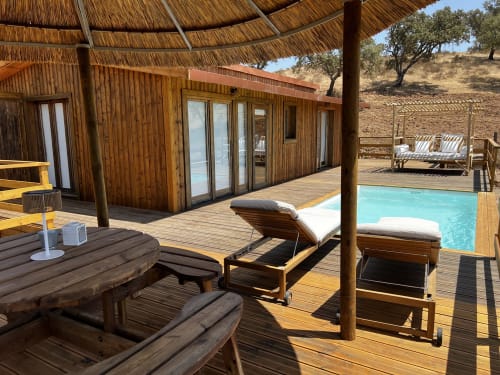 Pátio de luxo com piscina turquesa, deck de madeira, espreguiçadeiras, abrigo com cobertura de palha e vistas para a montanha em Almodôvar,