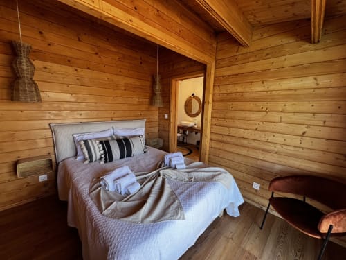 Quarto aconchegante com cama de casal, almofadas listradas e vigas rústicas na villa Corvatos Casas do Monte em Almodôvar.