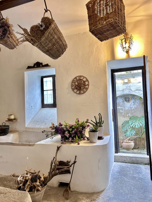 Stanza rustica imbiancata a calce presso Relais Palazzo Cacace a Meta di Sorrento, con cesti in vimini, orologio vintage e vista sul giardino