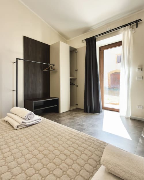 Camera moderna al Baglio Capo B&B di Siculiana con letto, cabina armadio nera e accesso alla terrazza