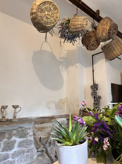 Interno rustico di Relais Palazzo Cacace con cesti intrecciati, fiori viola e camino in pietra a Meta di Sorrento