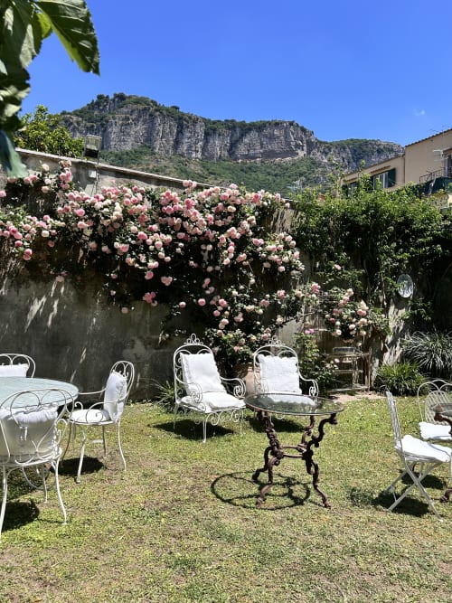 Incantevole terrazza giardino del Relais Palazzo Cacace a Meta di Sorrento con rose rosa fiorite e arredi in ferro battuto bianco