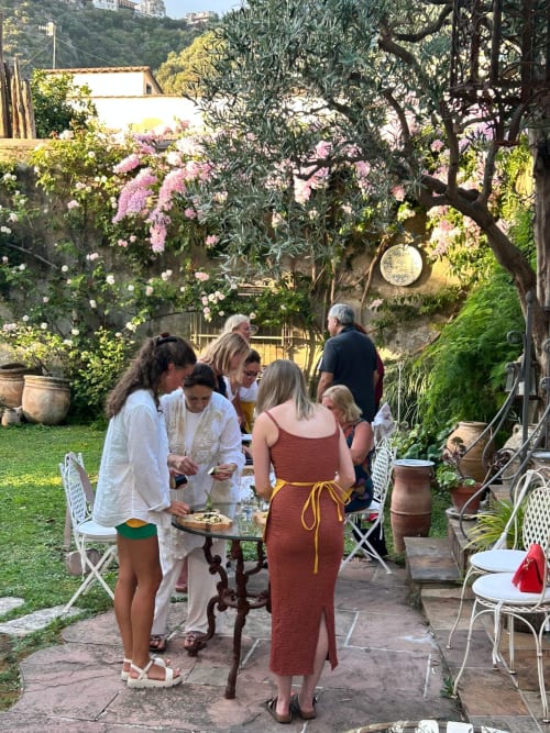 Ospiti che si divertono a un ricevimento in giardino presso il Relais Palazzo Cacace a Meta di Sorrento, circondati da fiori in fiore