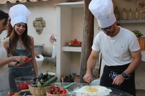 Lezione di cucina presso Relais Palazzo Cacace a Meta di Sorrento con chef e ospiti che preparano piatti italiani con ingredienti freschi