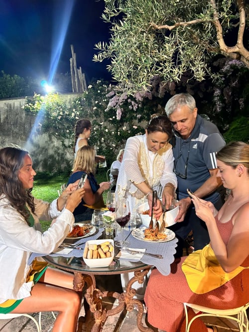 Cena all'aperto serale al Relais Palazzo Cacace, Meta di Sorrento, con ospiti che assaporano la cucina italiana in un'atmosfera elegantemente illuminata