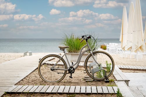 Bicicletta d'epoca con fioriera sulla spiaggia sabbiosa della promenade a Vahospitality, Francia, con ombrelloni vela e vista sul mare