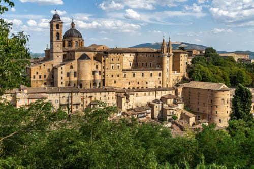 Antico borgo medievale arroccato su una collina con edifici storici in pietra, campanile e cupola a Urbino, regione Marche, Italia